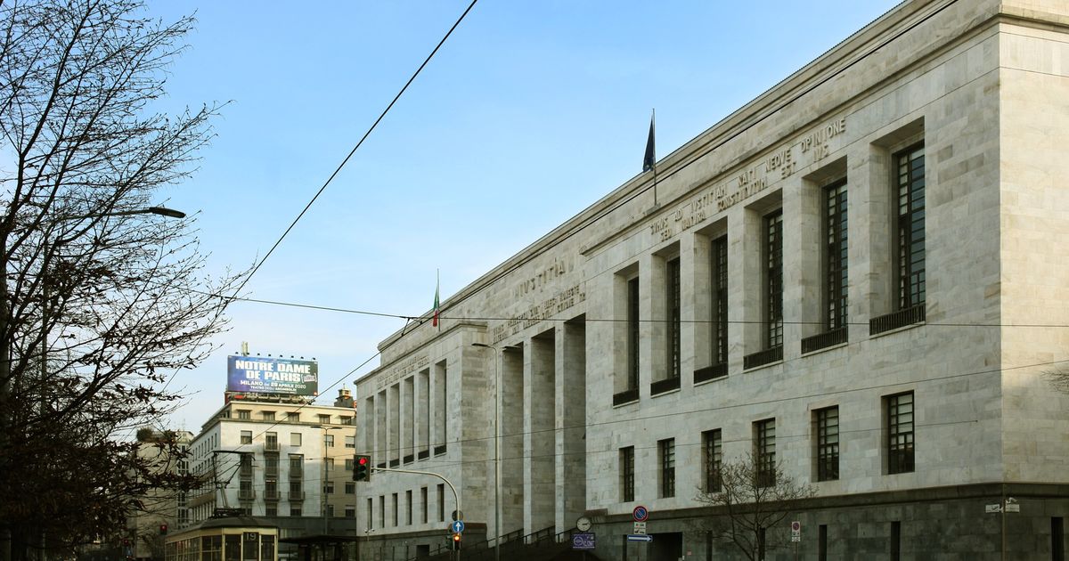 The Palazzo di Giustizia in Milan, a monumental white stone courthouse by Marcello Piacentini, seen along the street with a yellow tram passing.