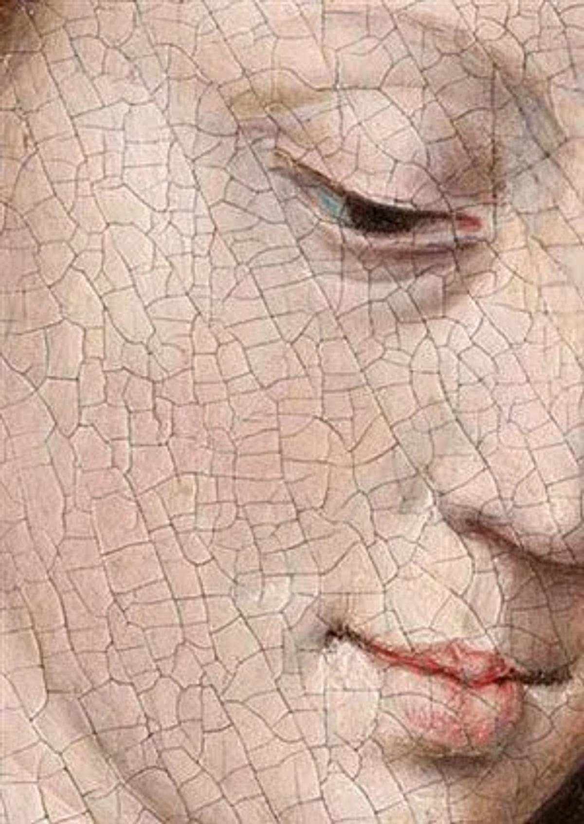 An extreme close view of a painted face, the whole surface covered in a fine web of craquelure running across the eye, cheek and lips.