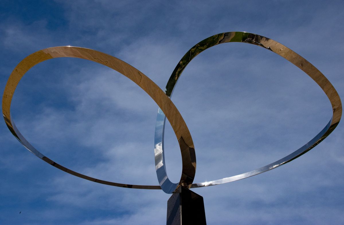 A second view of Infinity from below, its polished stainless steel ribbon looping twice against a blue sky above a dark granite base.