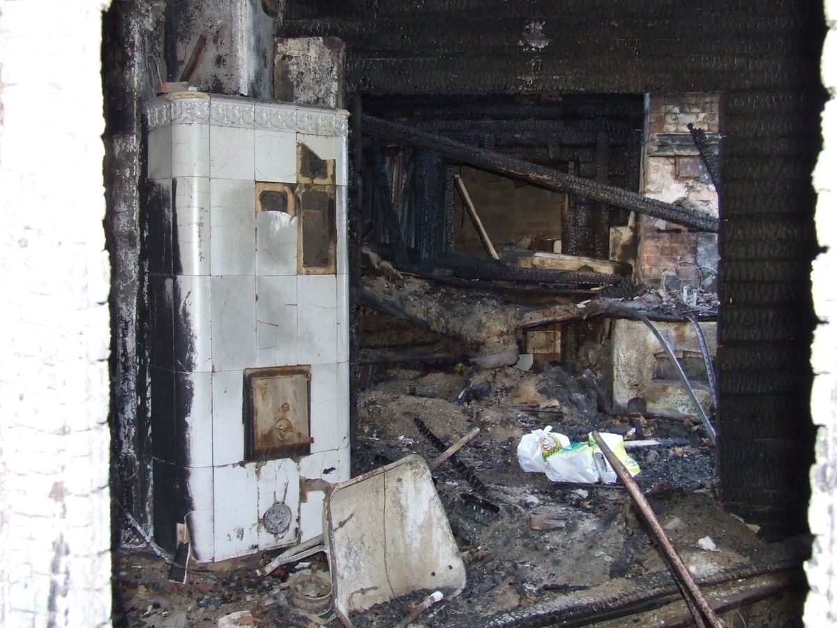 The burnt interior of a house, its walls charred and its contents destroyed.