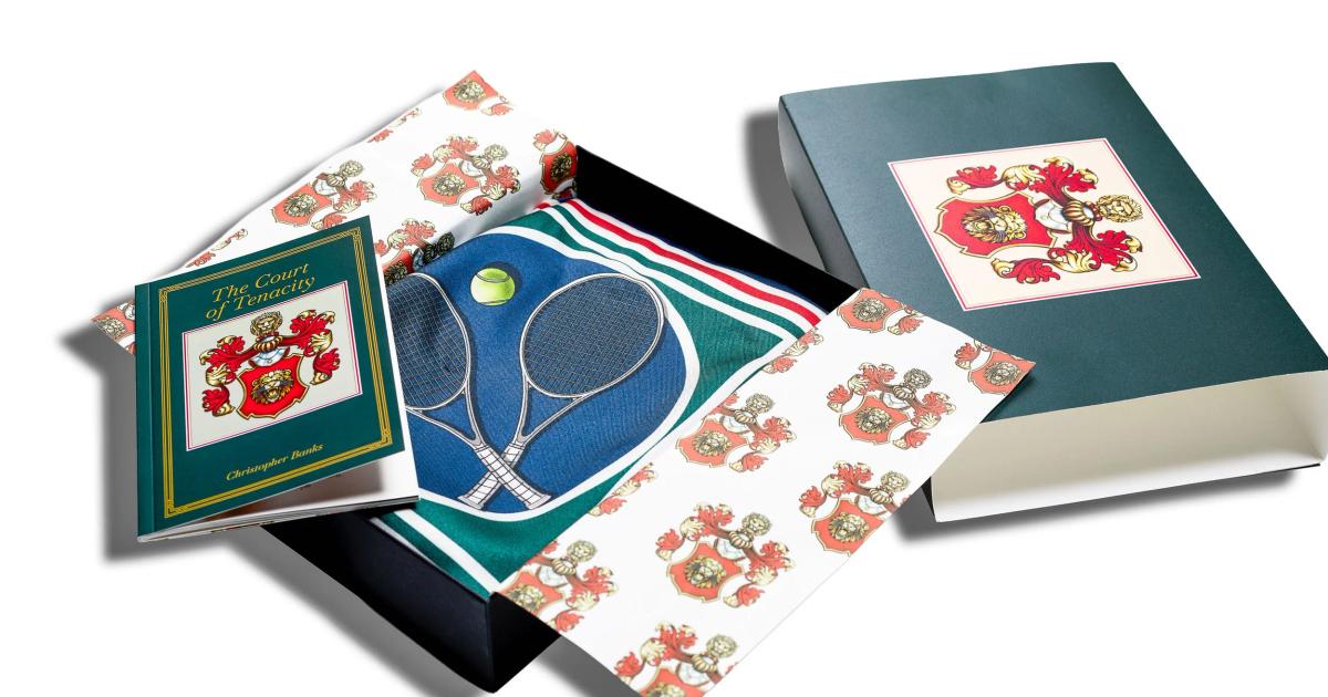 A boxed stationery set fanned out on a dark surface: cards and a cloth bound folder printed with a red and gold lion crest, and a green sheet showing crossed tennis rackets.