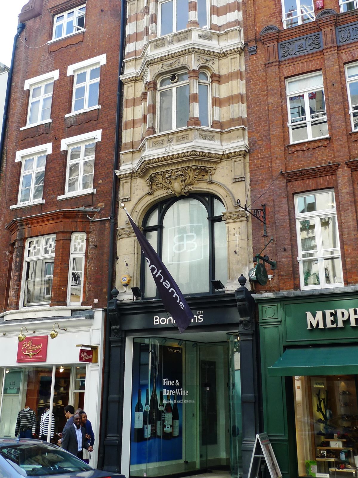 The Bonhams frontage on New Bond Street, London, with a purple Bonhams banner and a Fine and Rare Wine sale poster in the window.
