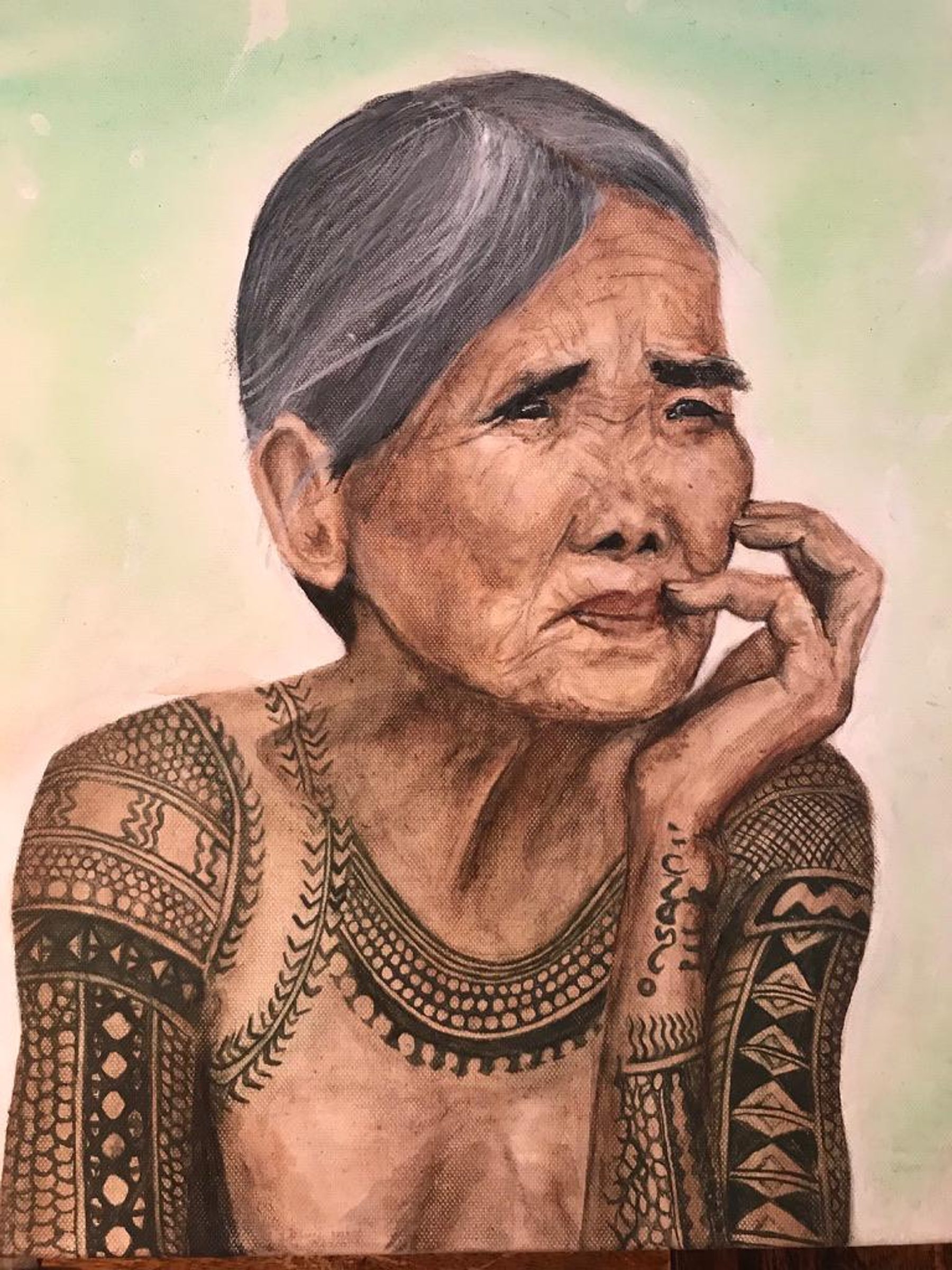 A portrait painting of an elderly woman with grey hair and patterned tattoo-like designs across her shoulders and arms, resting her face against one hand.