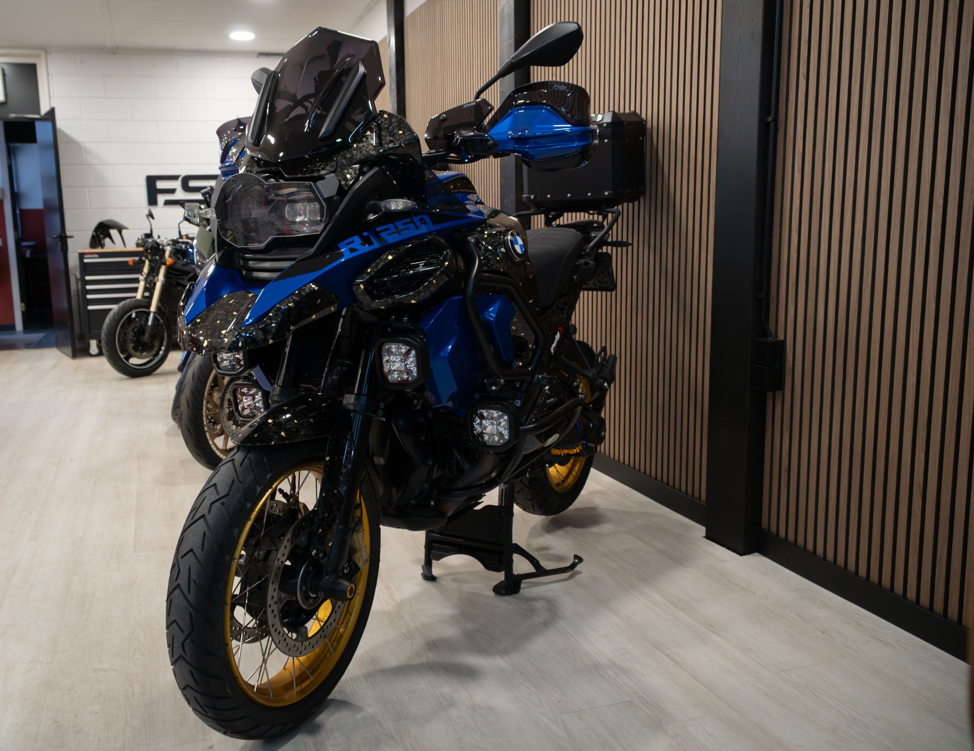 Blauwe BMW R1250GS met forged carbon en gouden velgen in de showroom