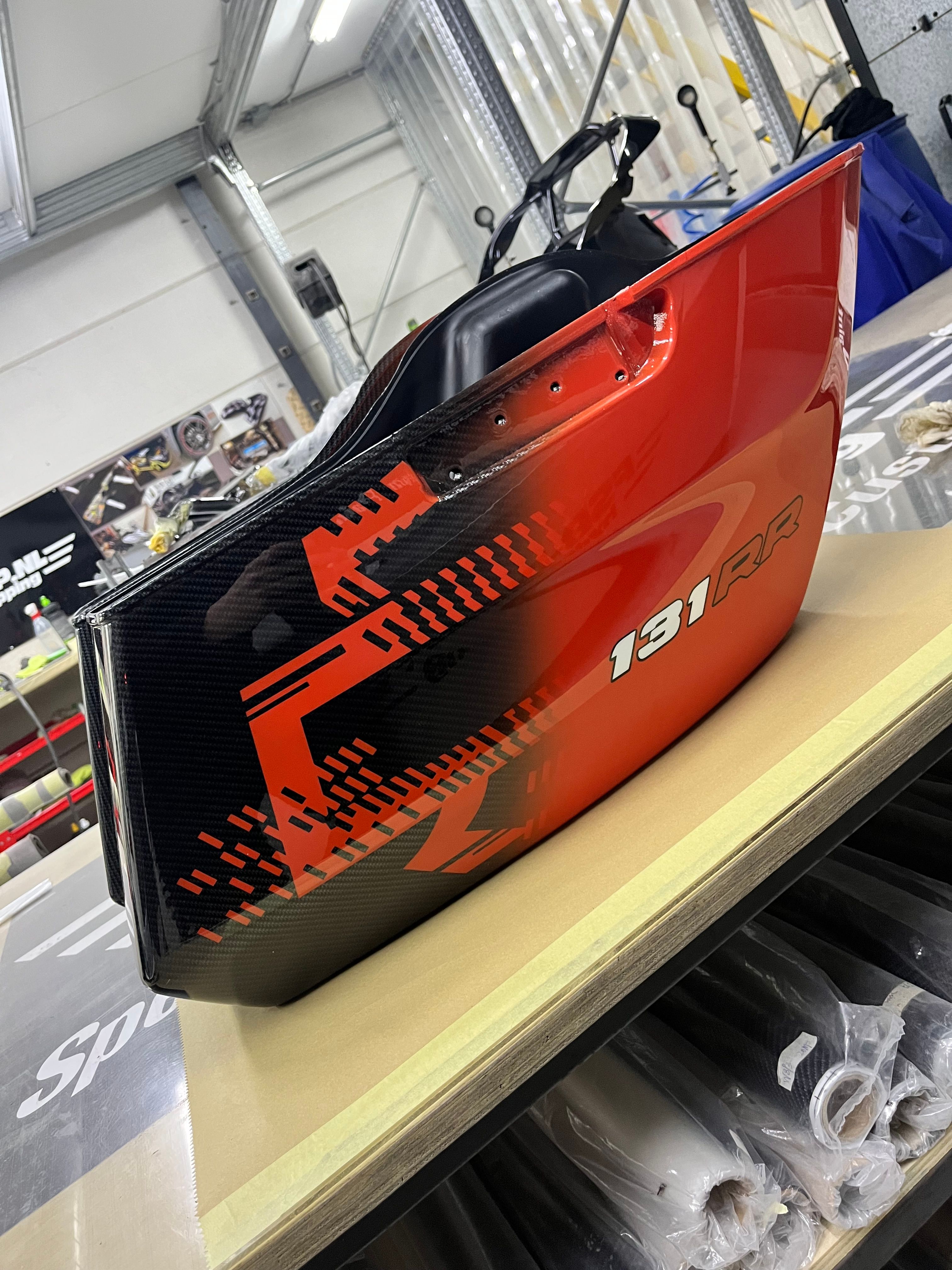 Koffer met oranjerood design over carbon en 131RR-belettering