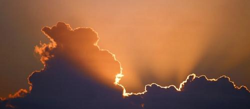 rays of orange sunlight burst from behind a dark cloud in the foreground | glimmers | ventral vagal | Tempo Therapy and Consulting