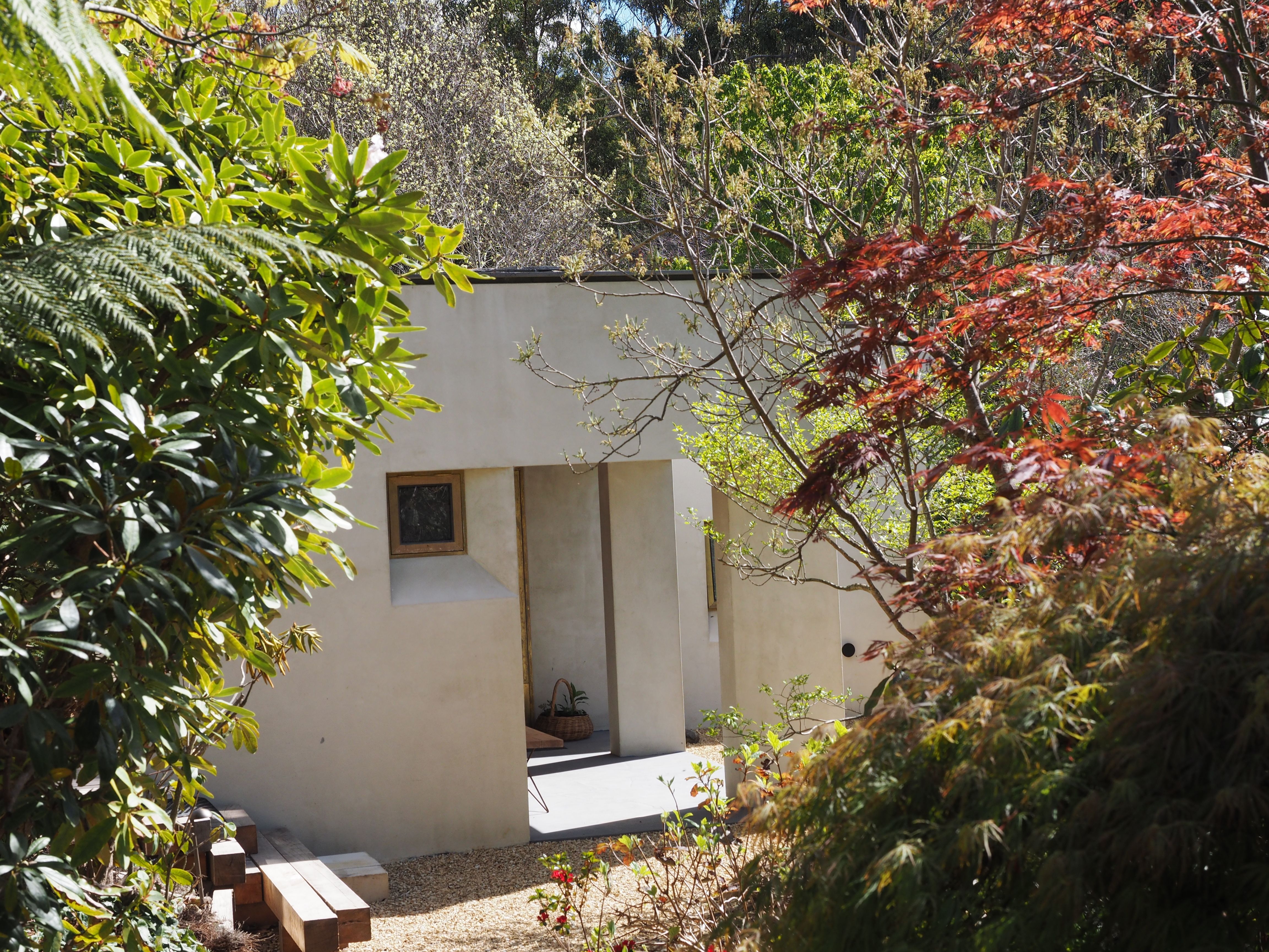 entrance to the South Hobart Garden Therapy Studio. A pale rendered building with a sheltered doorway, timber ceiling and brass-framed glass door. | Hobart Supervision Collective | Tempo Therapy and Consulting