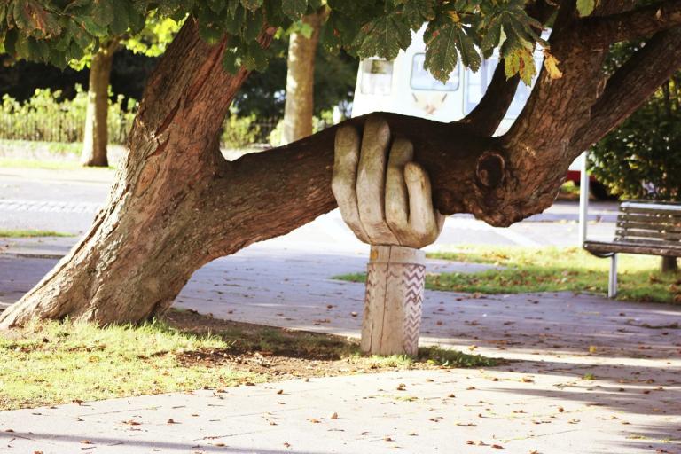 graffiti of two closed fists on a wall sit in partial sun and dappled shadow | anti-self care revolution | Tempo Therapy and Consulting