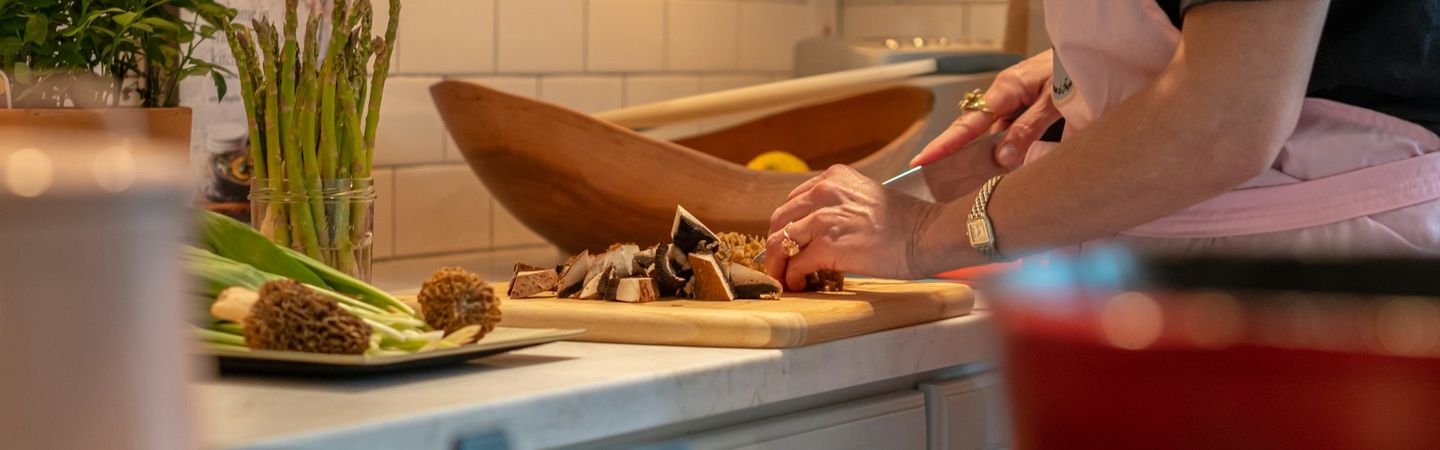 Profile of a white woman chopping vegetables in a warm-lit kitchen| Why the work stays with therapists and clinicians after sessions | Tempo Therapy and Consulting