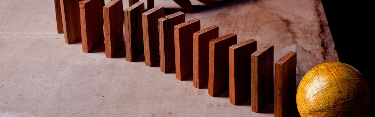 a line of wooden dominoes stand upright on a table, with the first few beginning to fall | Team supervision |Tempo therapy and Consulting