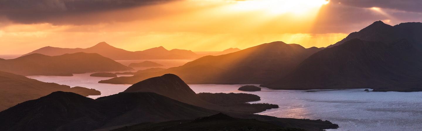 orange sun shine bursts through dark clouds over Port Davey | guided imagery and music | Tempo Therapy and Consulting