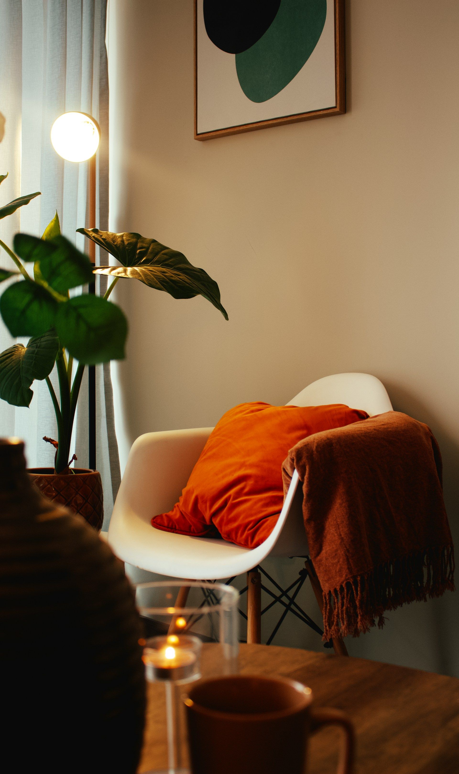 a cosy room corner with a white chair and orange cushion is lit by a warm lamp | therapy for therapists, clinicians and service leaders | Tempo Therapy and Consulting