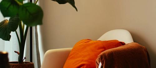 a cosy room corner with a white chair and orange cushion is lit by a warm lamp | therapy for therapists, clinicians and service leaders | Tempo Therapy and Consulting