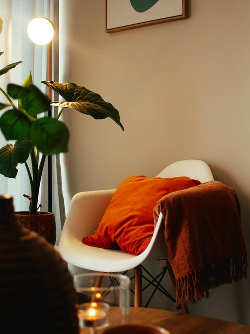 a cosy room corner with a white chair and orange cushion is lit by a warm lamp | therapy for therapists, clinicians and service leaders | Tempo Therapy and Consulting