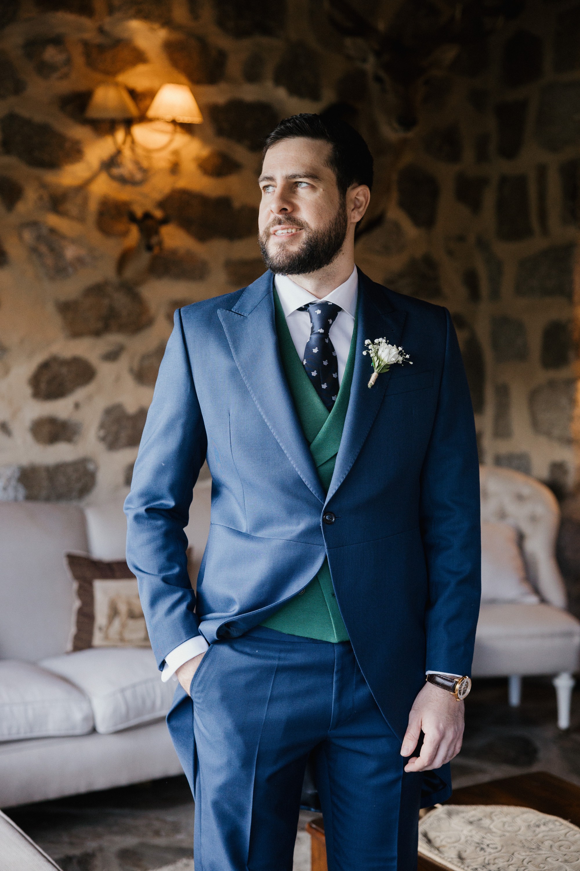 El novio, ya vestido de azul con chaleco verde, mira por la ventana antes de salir hacia la iglesia