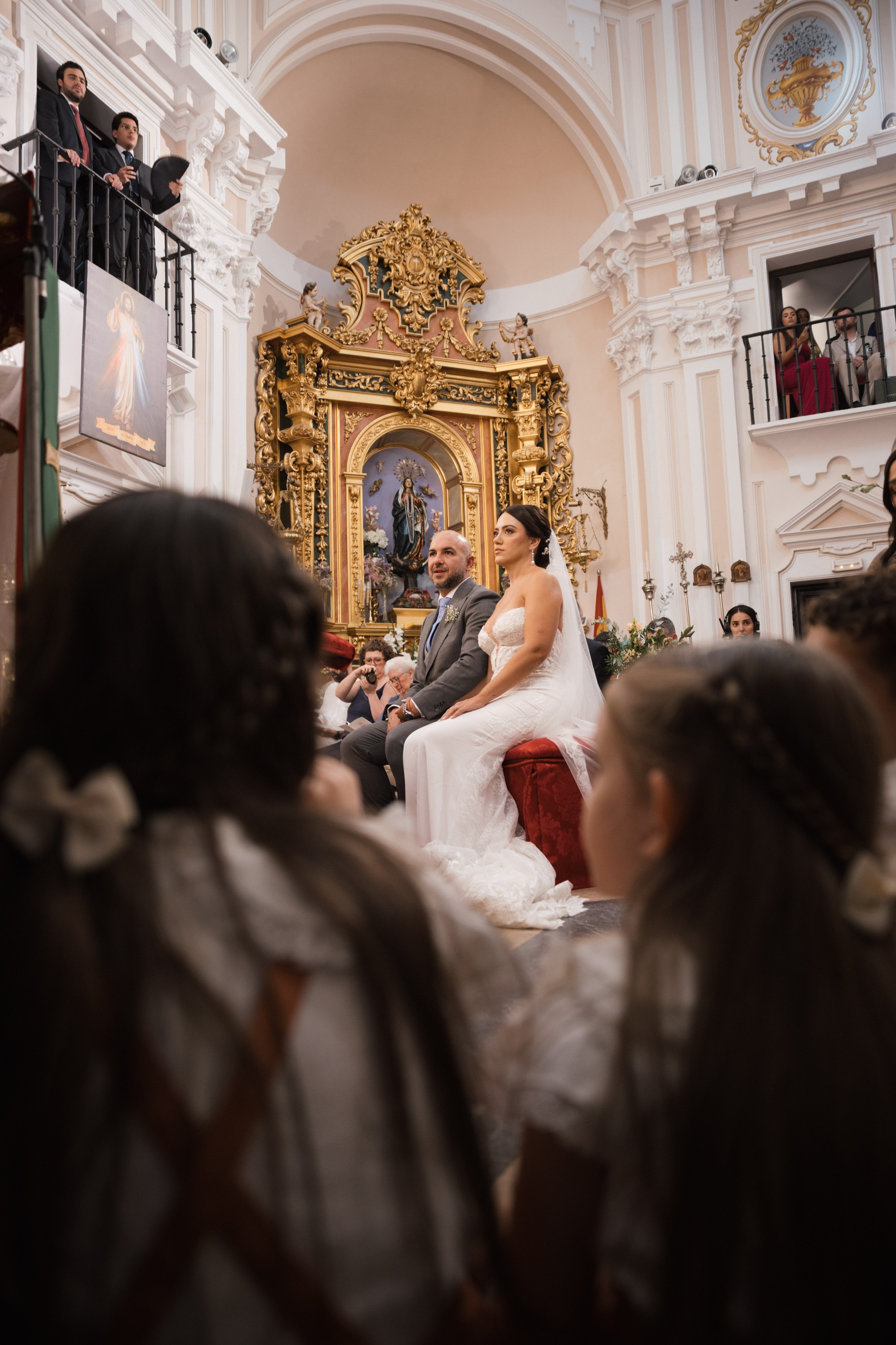 Los novios siguen la ceremonia vistos entre dos niñas con lazos blancos en el pelo