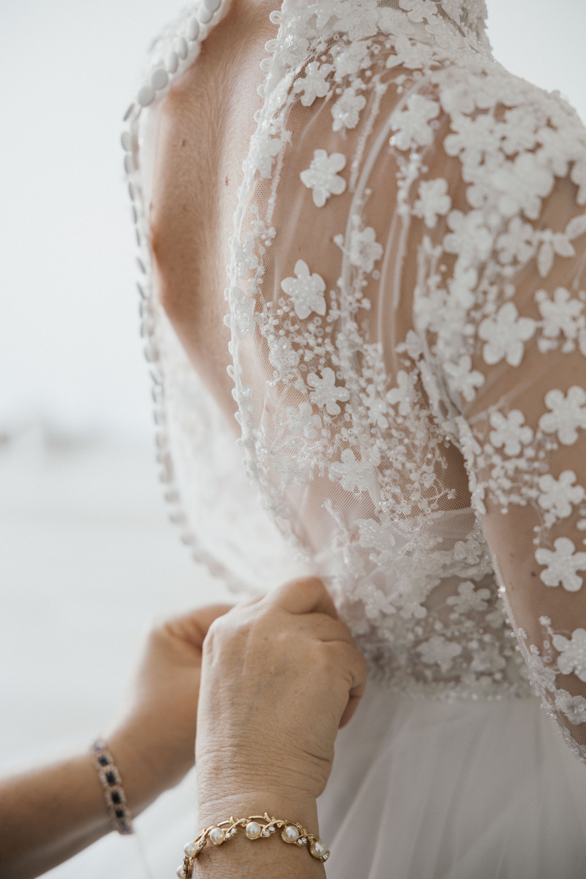 Unas manos abrochan los botones forrados de la espalda del vestido de encaje