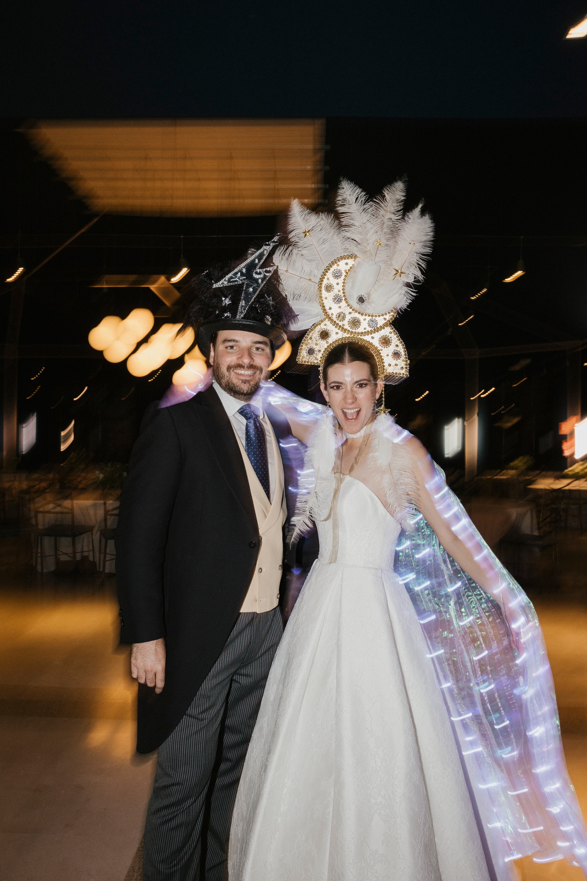 Los novios posan con sombrero de lentejuelas y una capa de luces en plena fiesta