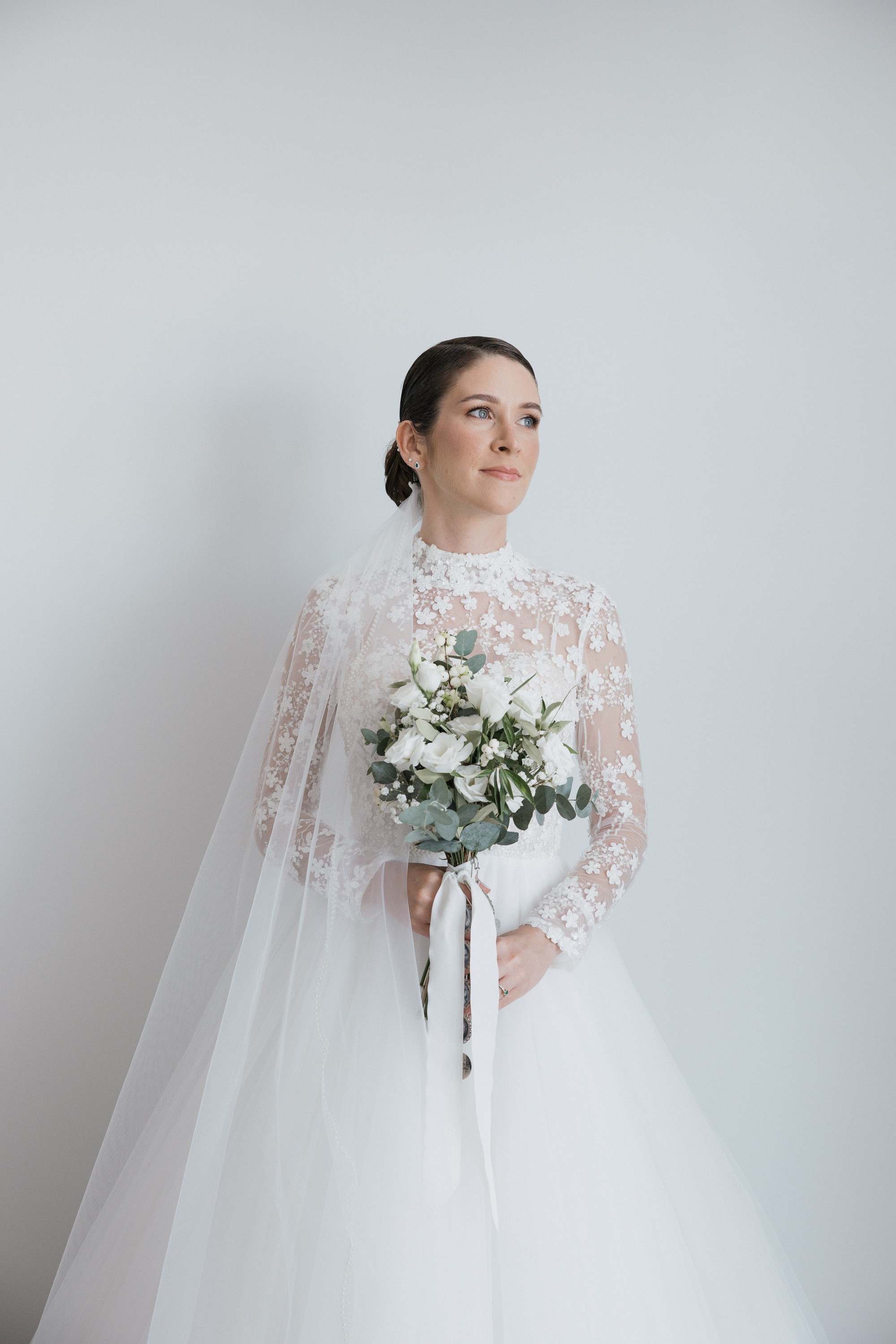 Retrato de la novia con el ramo de rosas blancas y eucalipto antes de salir hacia la iglesia