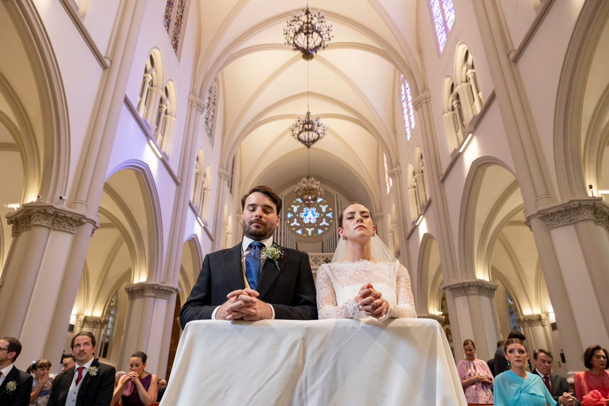 Los novios rezan con las manos entrelazadas bajo las bóvedas de la iglesia
