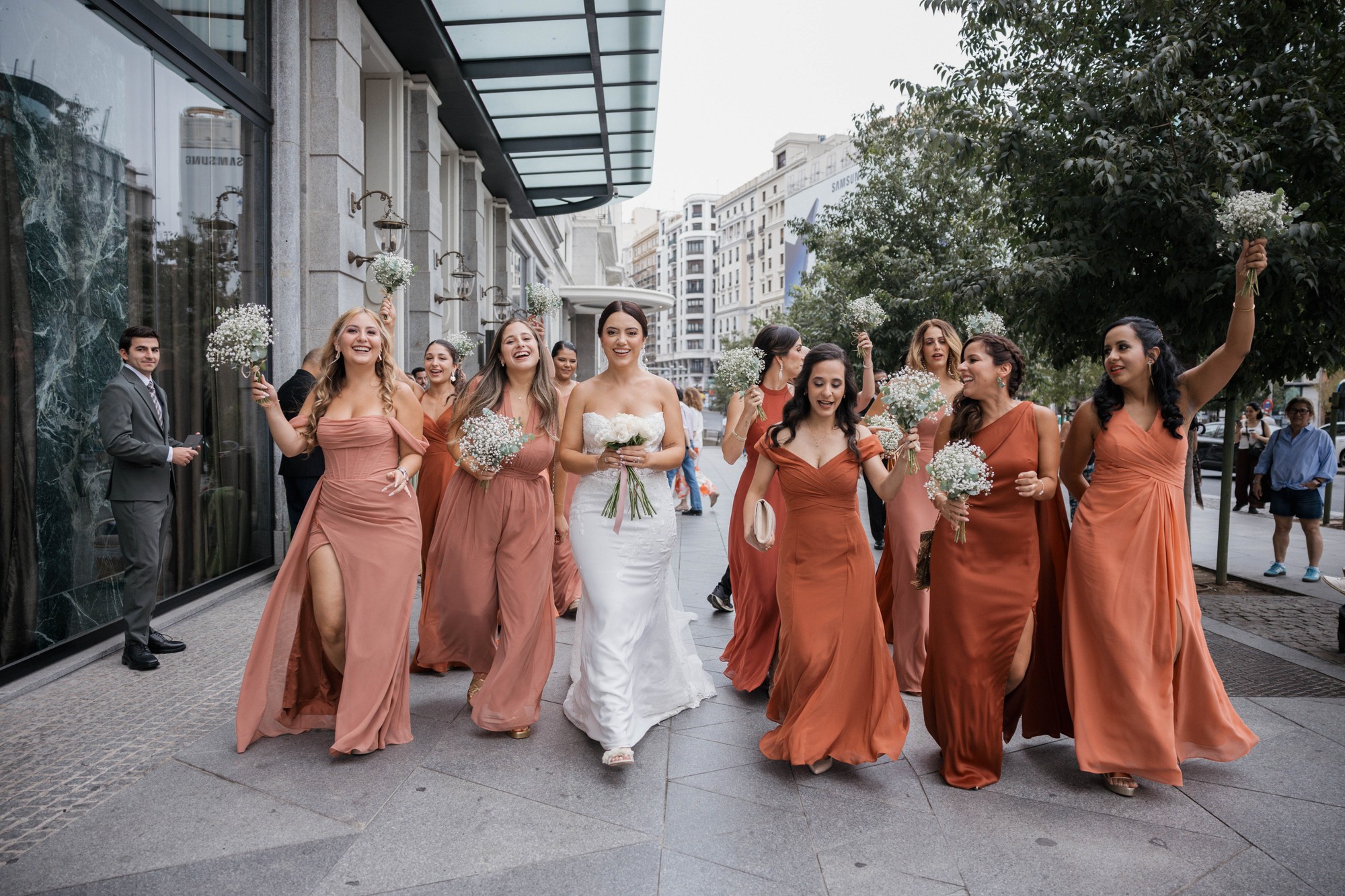 La novia camina por el centro de Madrid rodeada de sus amigas, que alzan ramos de paniculata