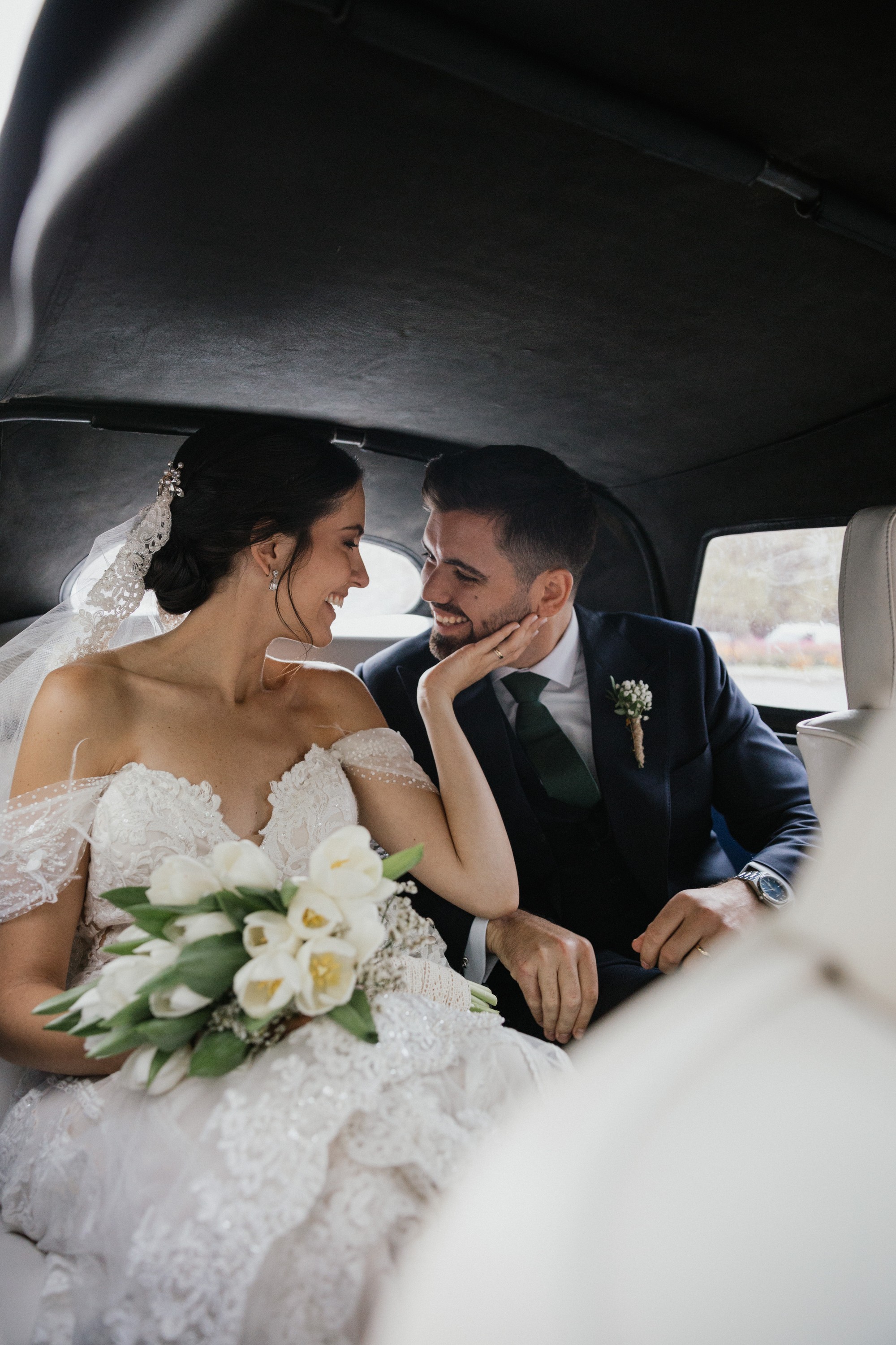 En el asiento trasero del coche, la novia acaricia la mejilla del novio