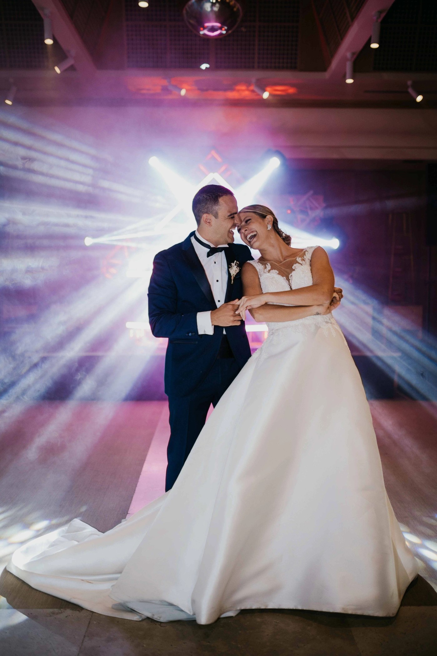 Los novios bailando en un camino bajo un cielo de nubes