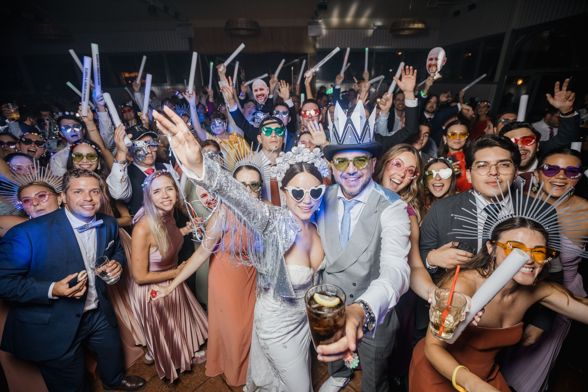 Todos los invitados se agolpan alrededor de los novios en la pista con los brazos en alto