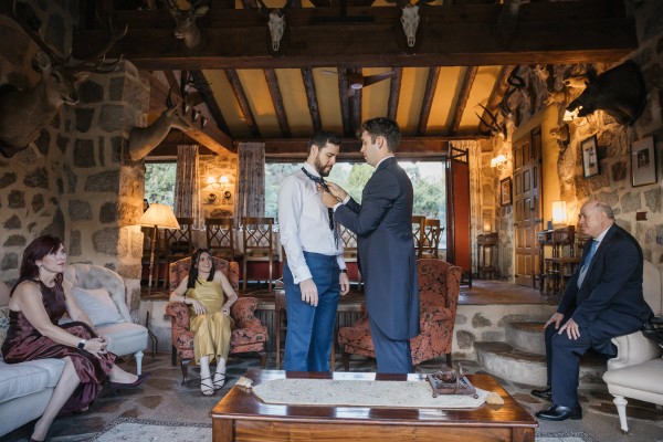 Guests watch as the groom's tie is knotted in the stone sitting room