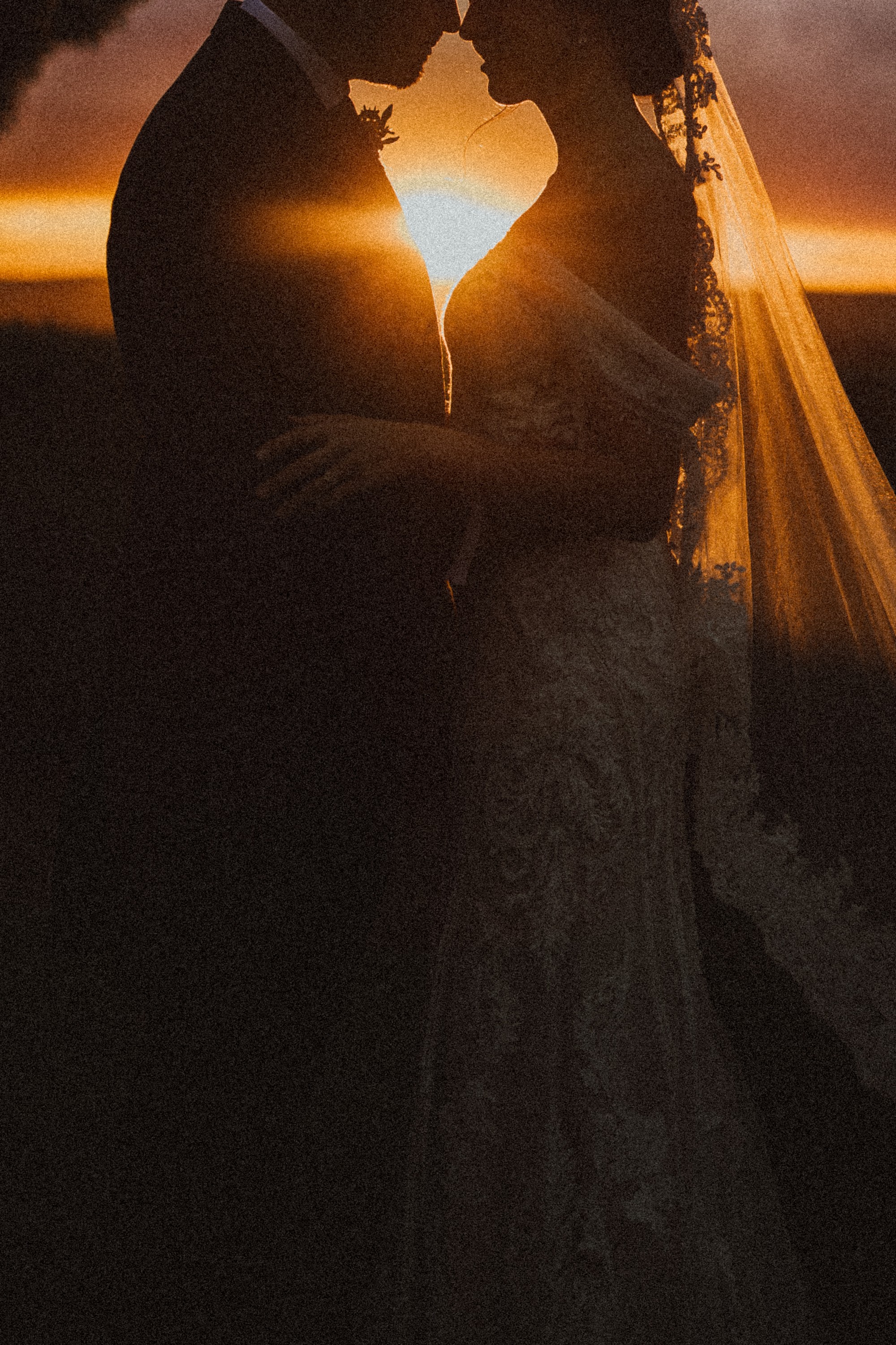 Los novios, frente con frente, recortados contra el sol del atardecer