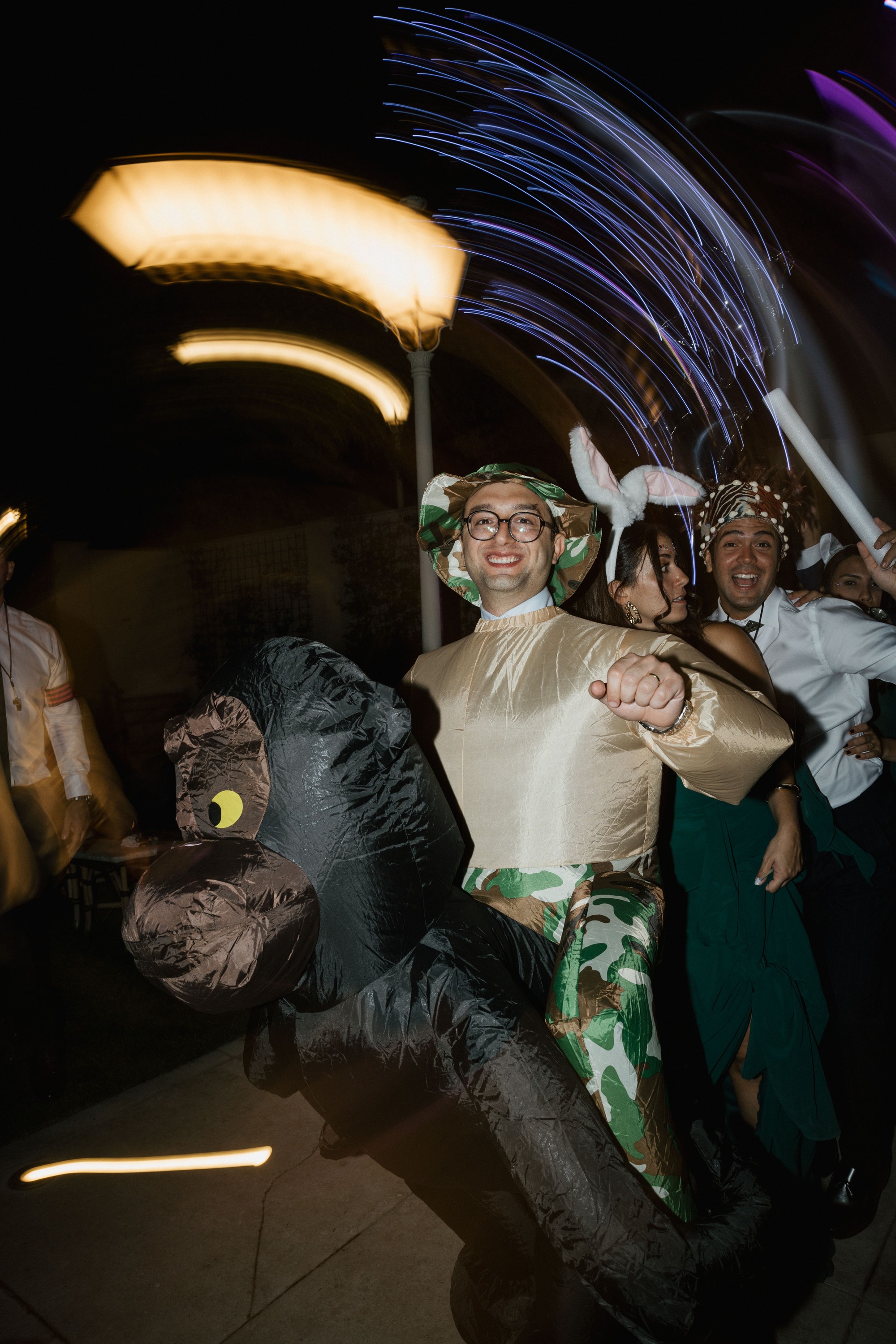Un invitado baila con un disfraz hinchable entre estelas de luces de colores