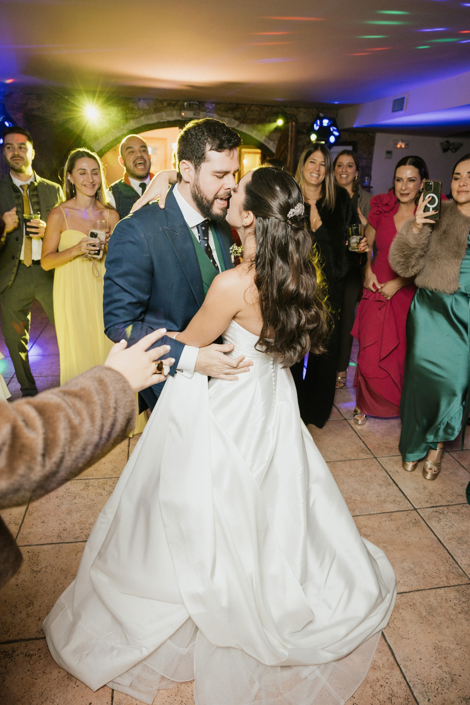 Los novios se besan en el centro de la pista rodeados por los invitados