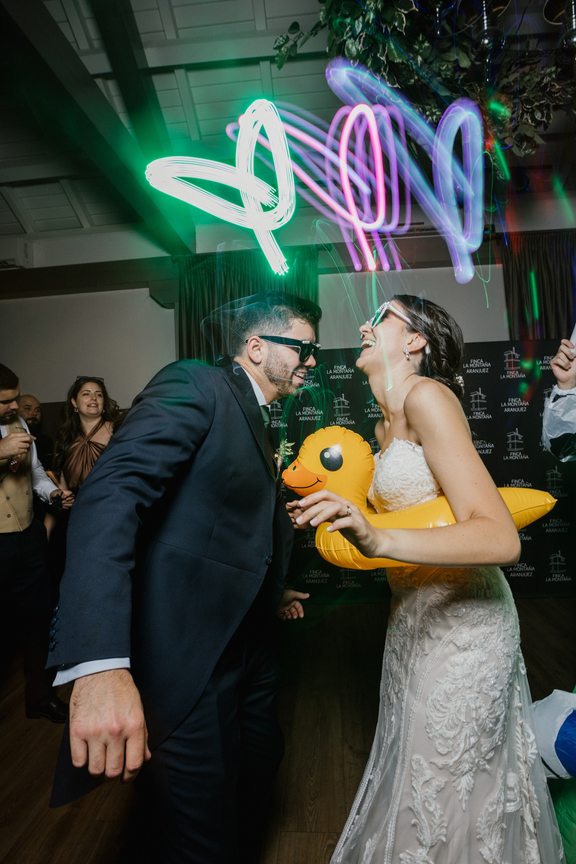 Los novios se ríen a carcajadas en la pista bajo los trazos de neón