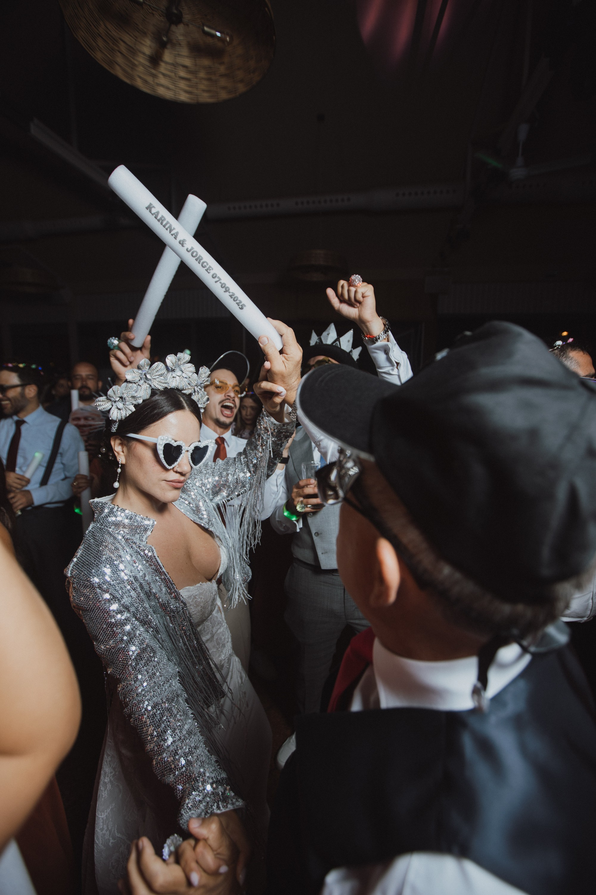 La novia baila entre los invitados con chaqueta de lentejuelas y corona de flores