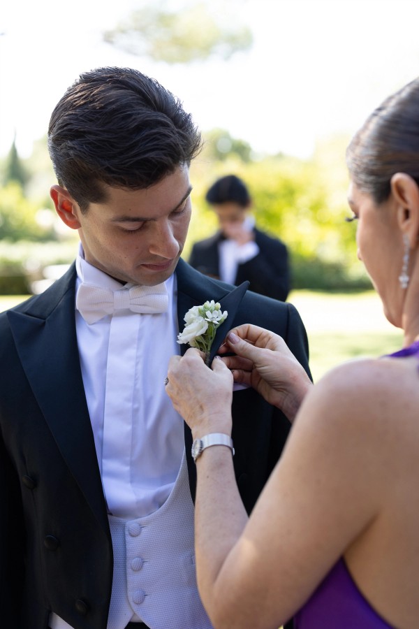 Pinning the boutonnière on the groom's lapel before the ceremony