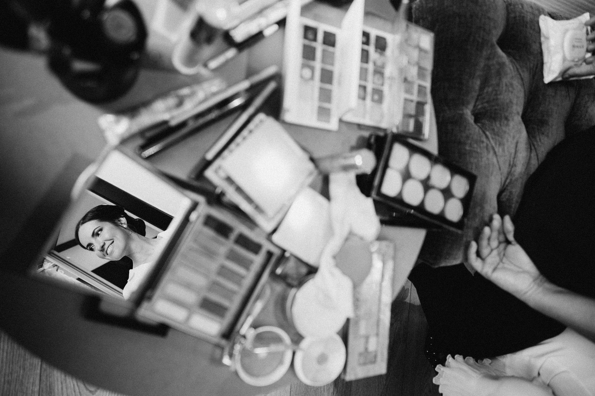 El rostro de la novia se refleja en un espejo entre las paletas de maquillaje