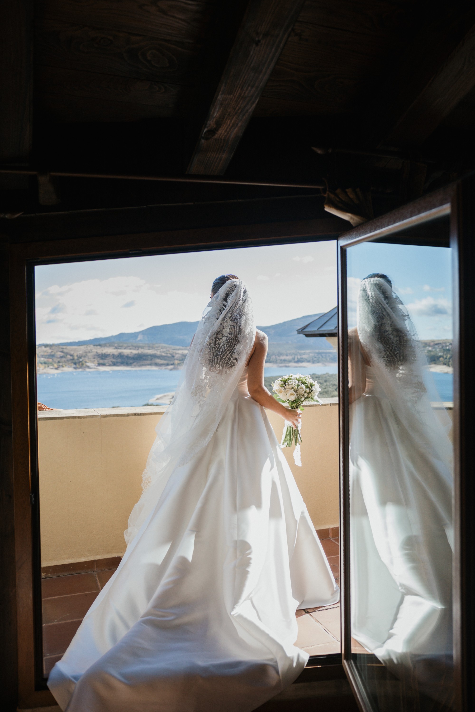 La novia se asoma al balcón con el embalse y la sierra al fondo