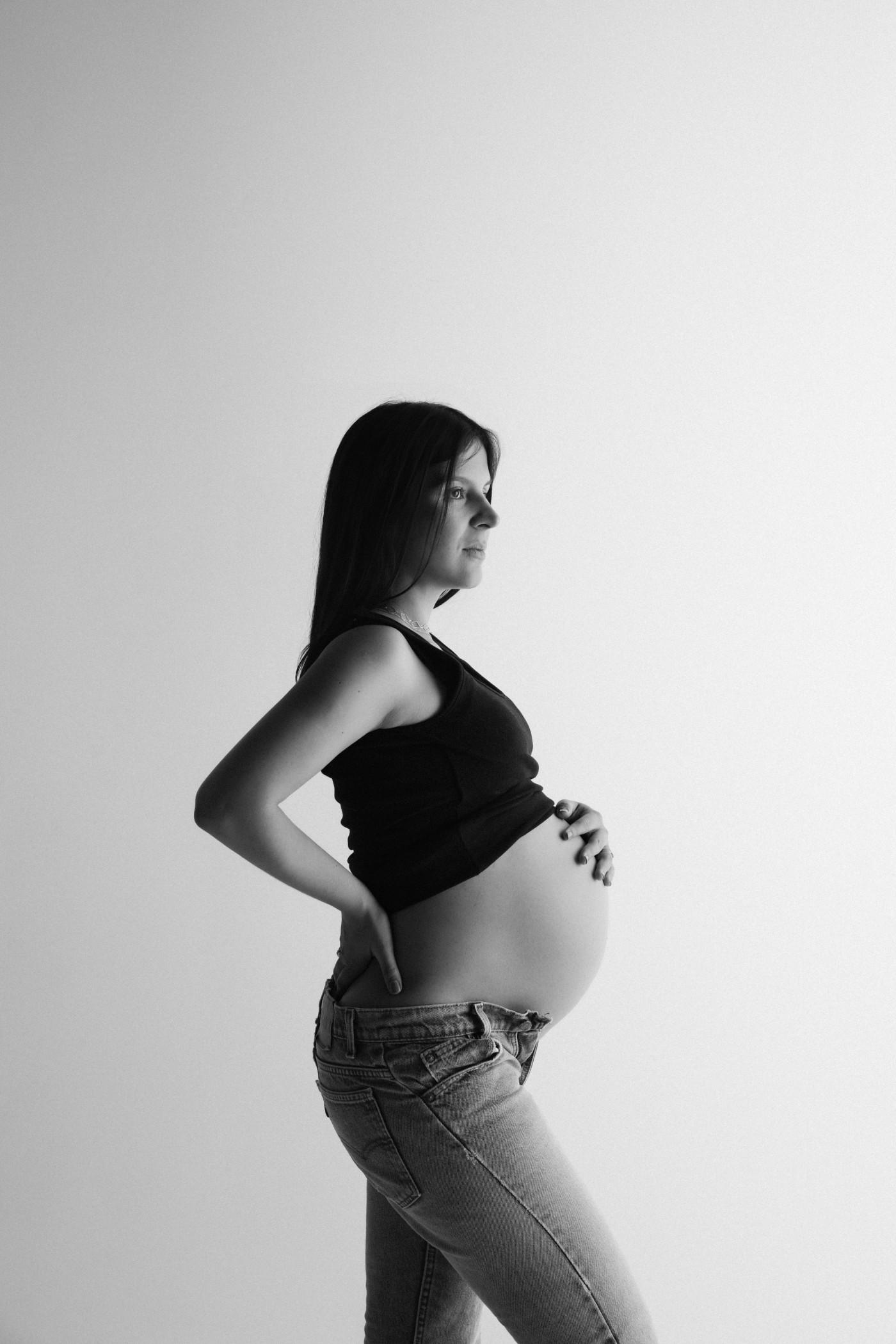 Embarazada de perfil con las manos en la barriga, en blanco y negro