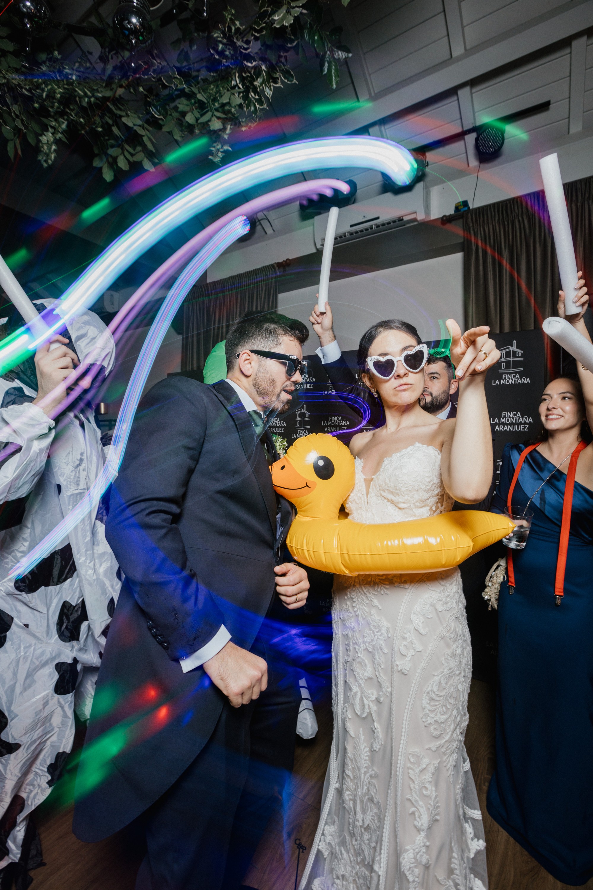 Los novios bailan con gafas de corazón mientras las luces dibujan trazos en el aire