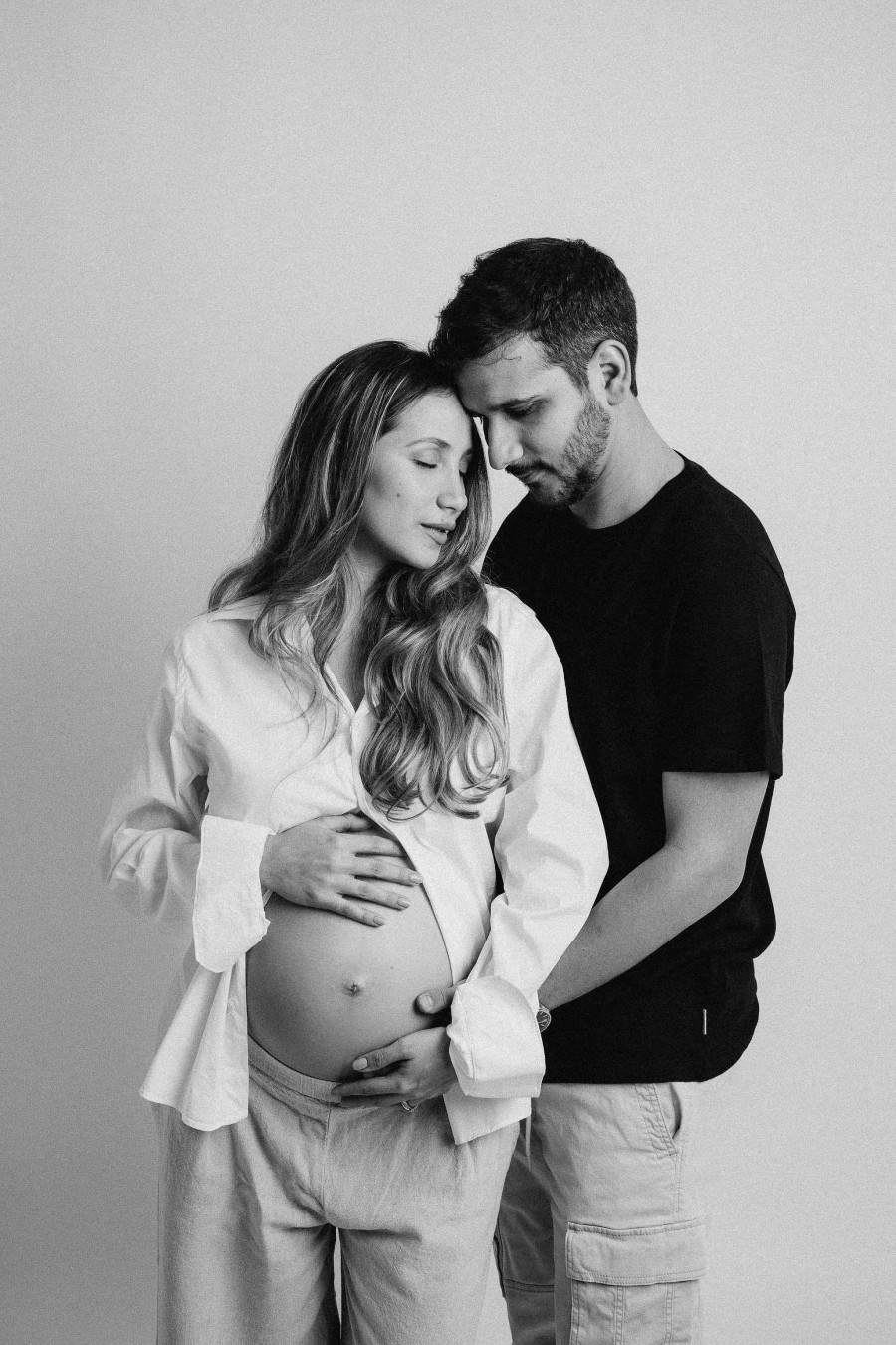 Couple embracing in a studio maternity session, black and white