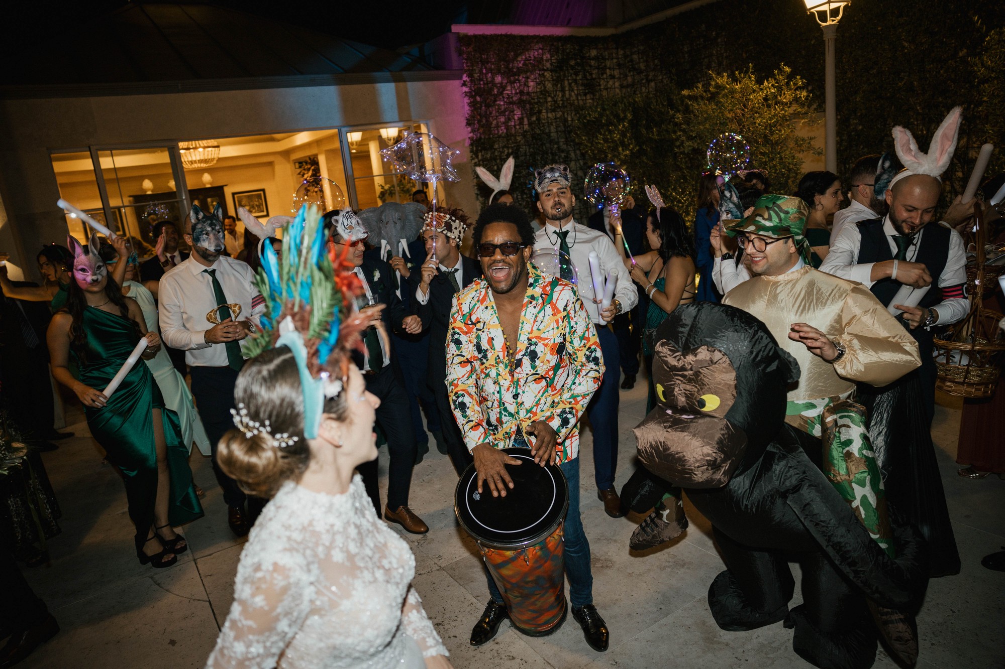 Un percusionista toca el tambor mientras los invitados bailan con máscaras y globos luminosos