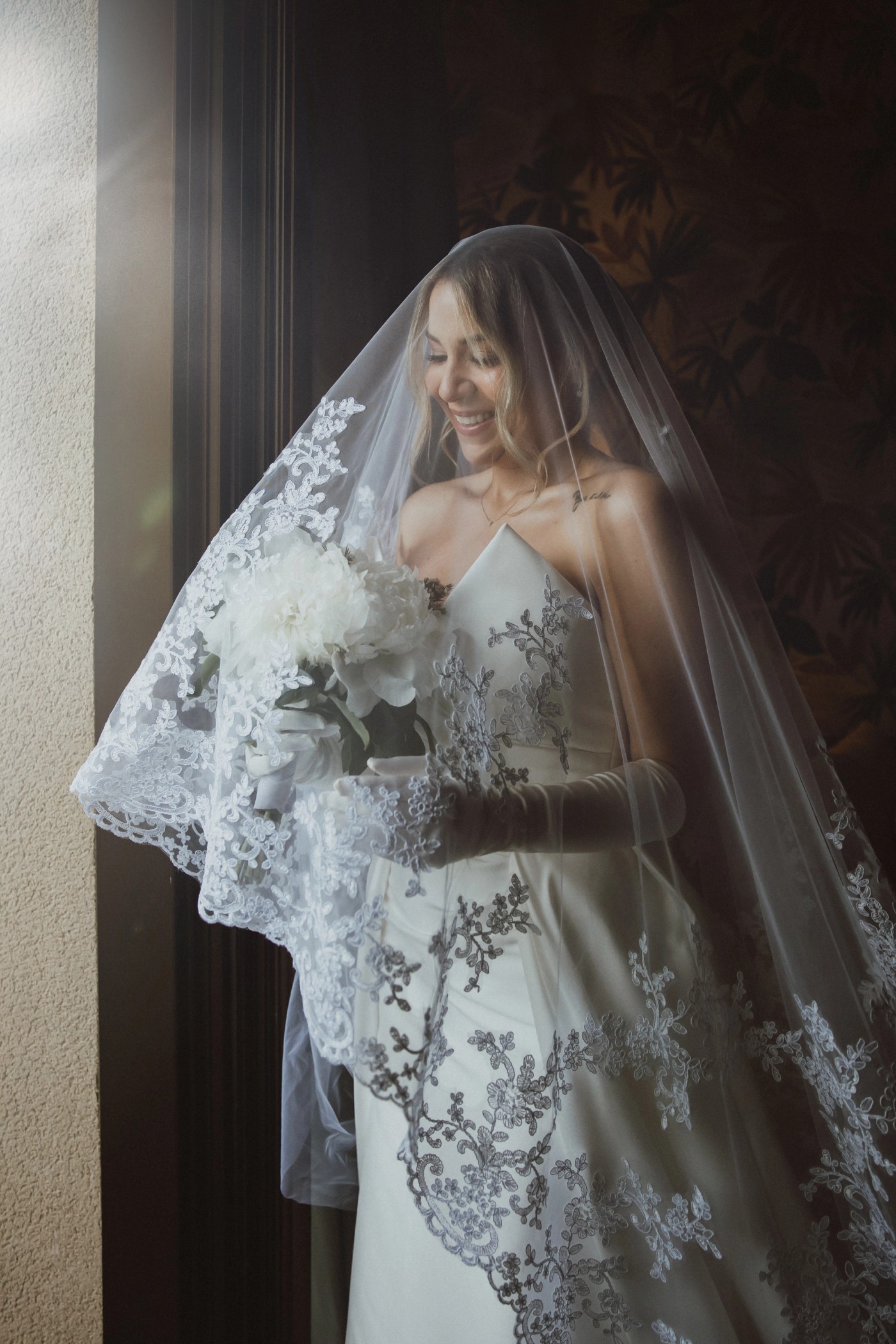 The bride's veil wrapping the couple against the light, in black and white