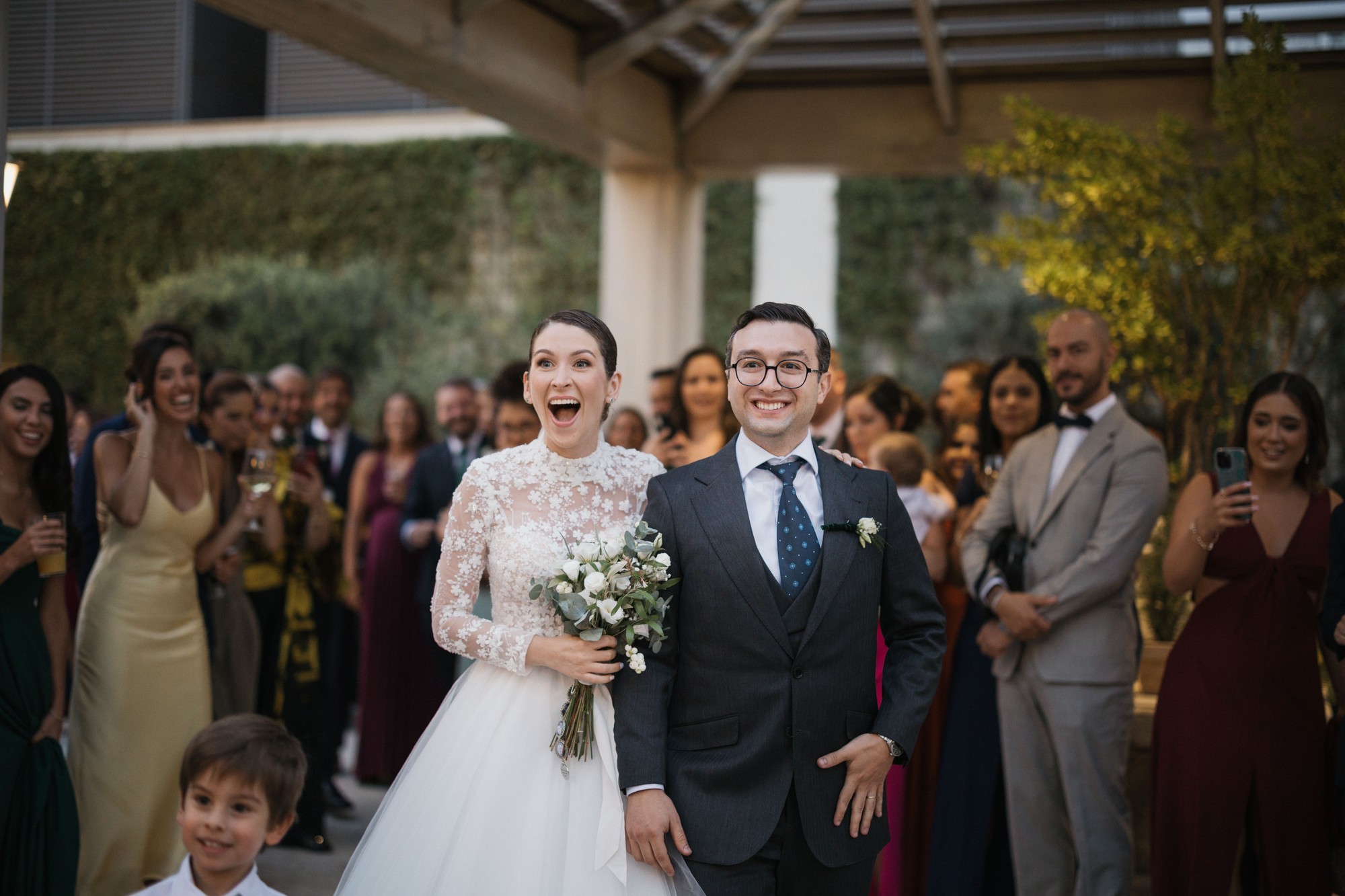 Los novios llegan al cóctel bajo la pérgola y los invitados los reciben con aplausos