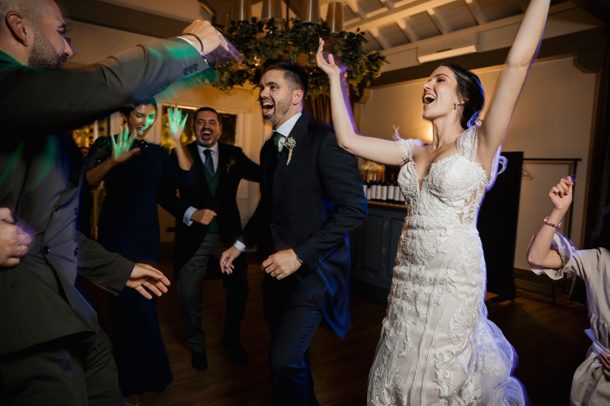Los novios bailan rodeados de invitados con los brazos en alto