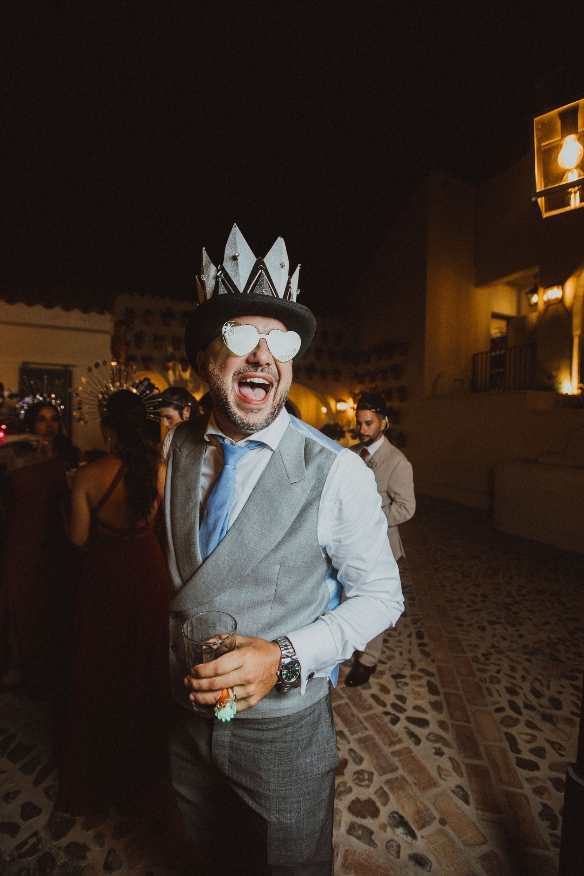 El novio celebra la fiesta con una chistera coronada y gafas de corazones