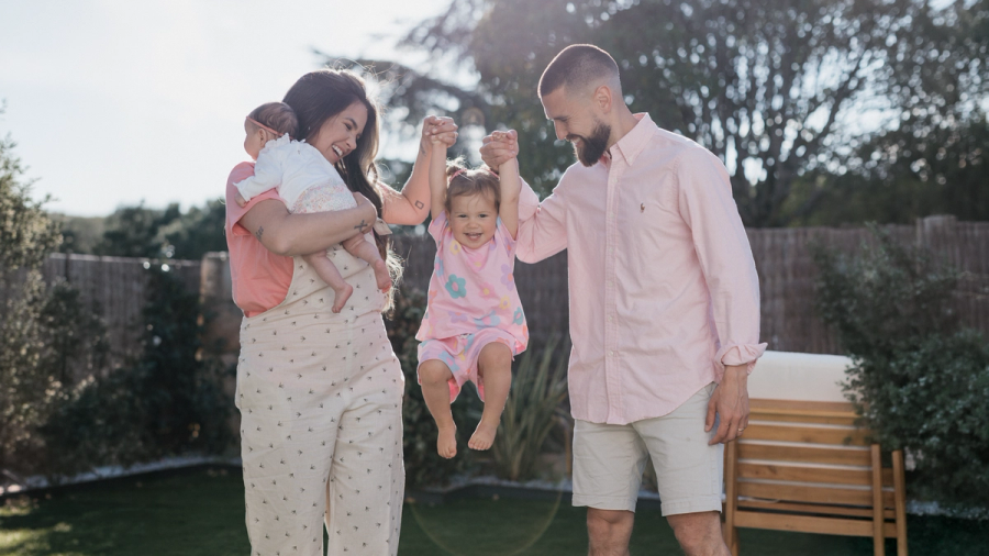 Padres columpiando a su bebé en una sesión familiar al aire libre