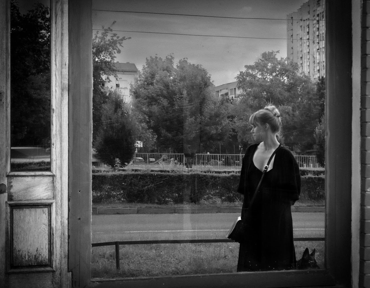A woman standing behind a window, photographed in black and white
