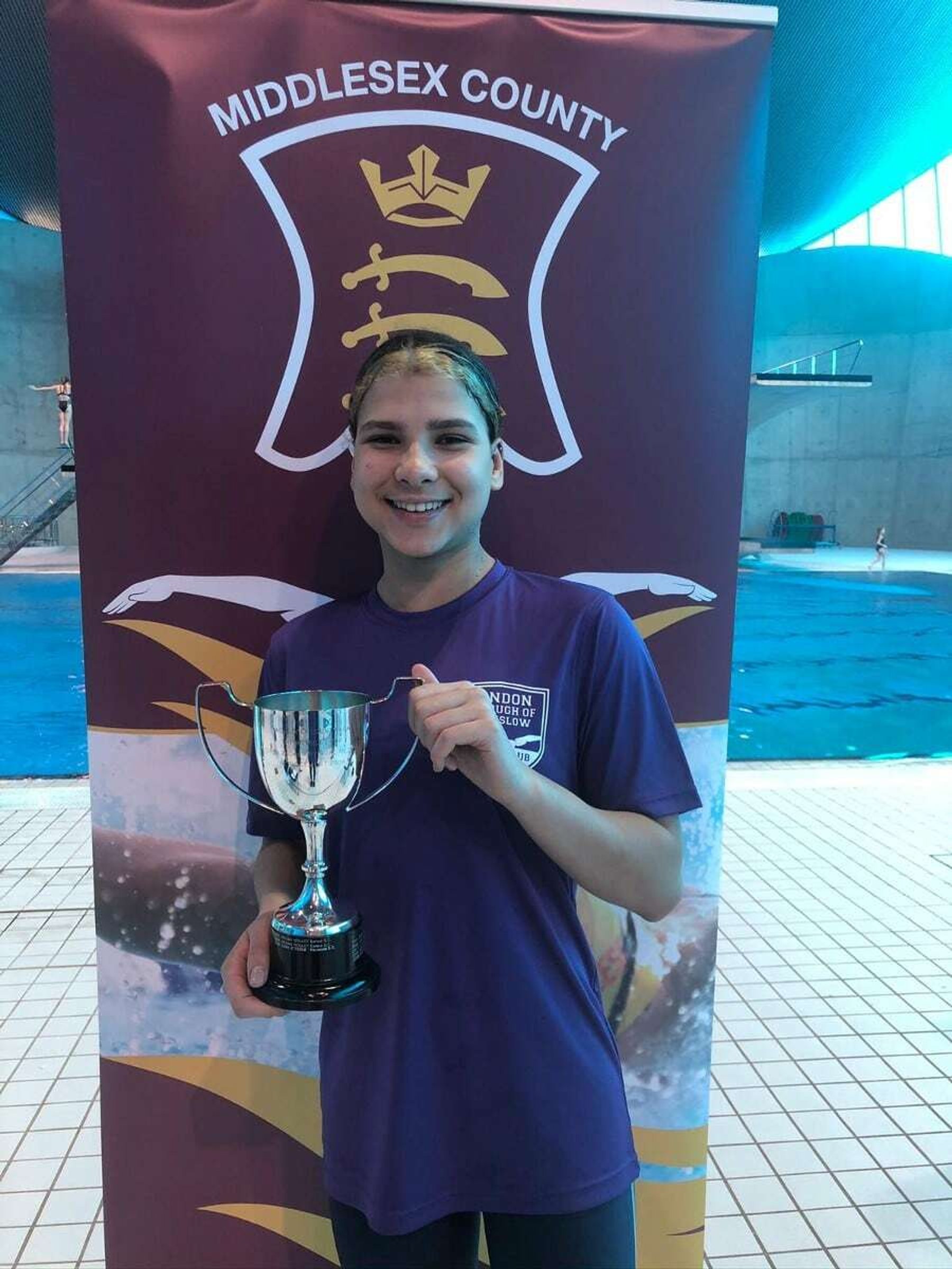An LBHSC swimmer holding a trophy at the Middlesex County championships
