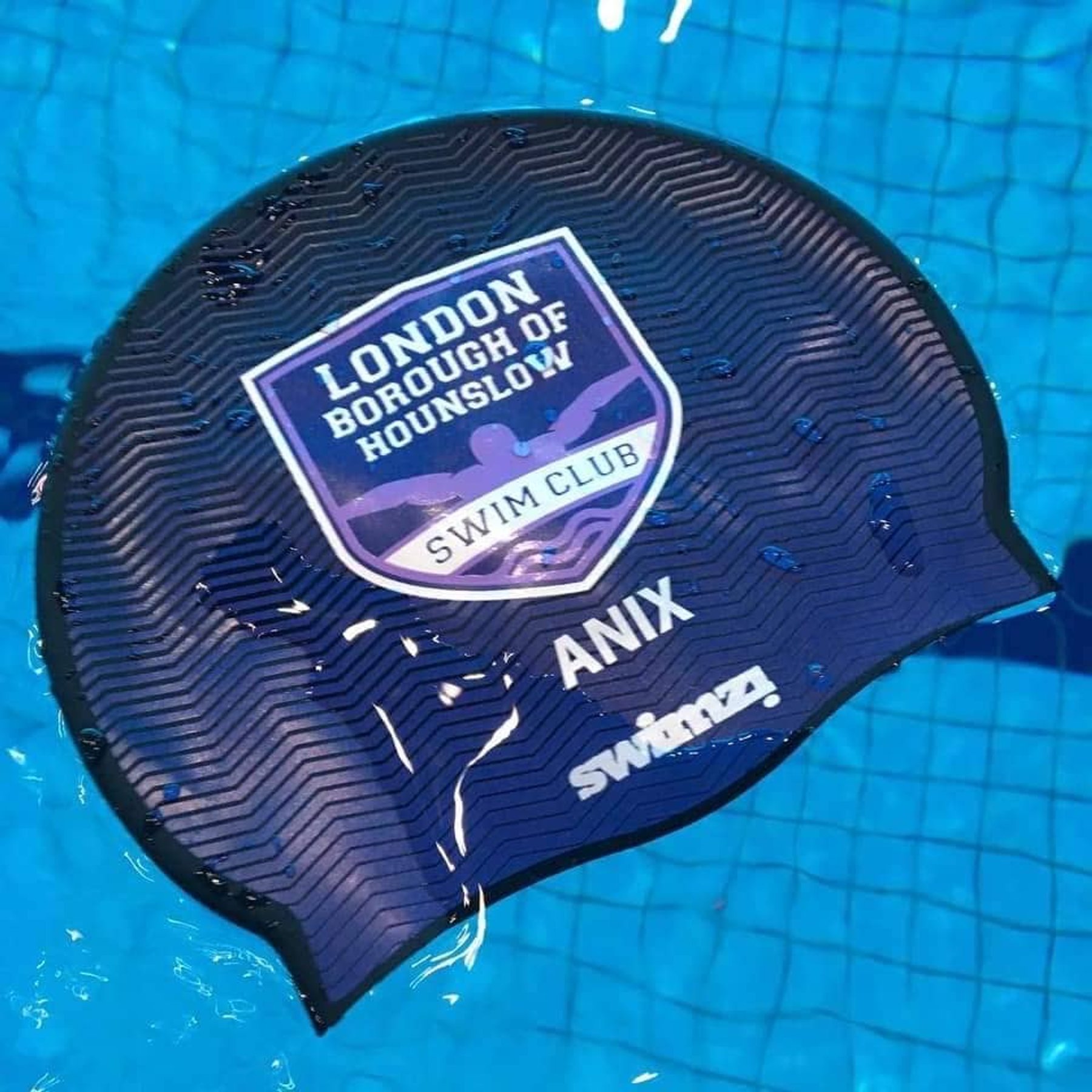 An LBHSC swim cap floating on the water