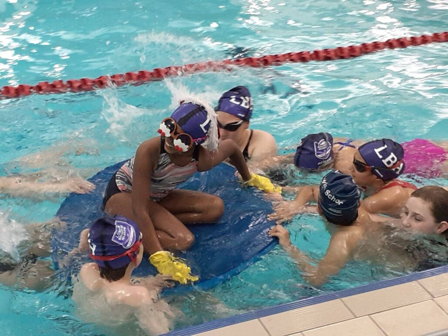 Squad swimmers working together on a large mat in the pool